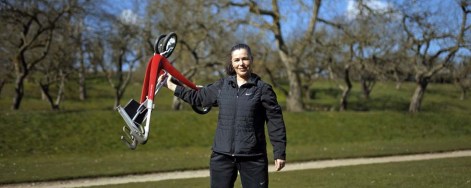 Frau hebt roten Rollator mit einer Hand hoch