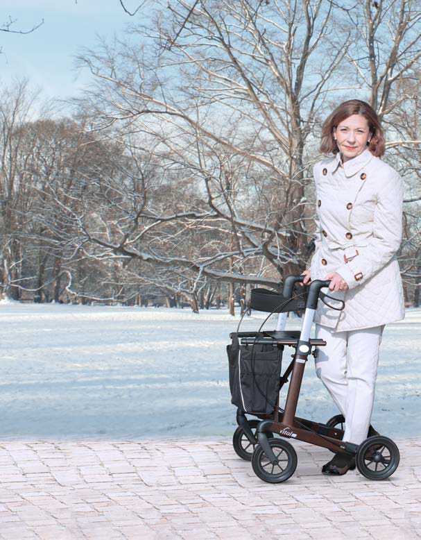 Frau geht am Rollator in Schneelandschaft