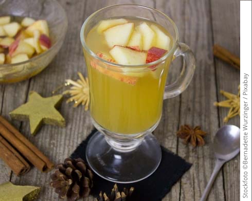 Apfelpunsch im Glas auf Holzbrettchen