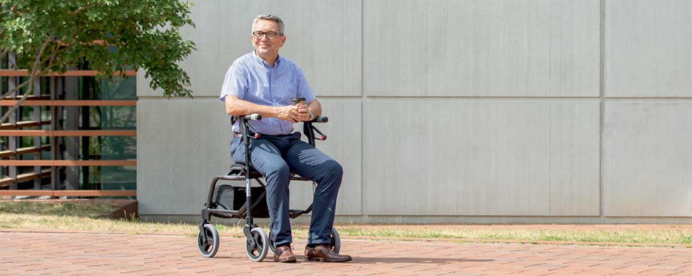 Mann sitzt auf Rollator Nexus